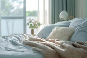 A bed with a blanket and pillows in front of a window photo