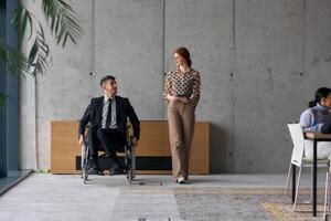 Director in a Wheelchair Engaging in a Business Discussion with a Colleague While Navigating a Modern Office photo