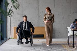 Director in a Wheelchair Engaging in a Business Discussion with a Colleague While Navigating a Modern Office photo