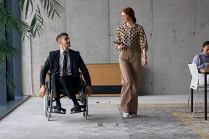 Director in a Wheelchair Engaging in a Business Discussion with a Colleague While Navigating a Modern Office photo