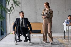 Director in a Wheelchair Engaging in a Business Discussion with a Colleague While Navigating a Modern Office photo