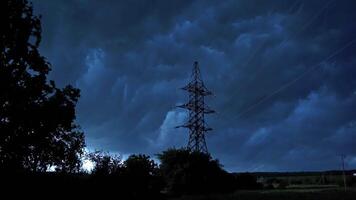 Stormy weather in nature. Dark clouds moving on the sky over the tower of high voltage electricity. Strong wind shaking trees in the evening. video