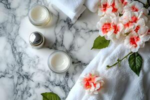 A marble table with white towels, a bottle of cream and flowers photo