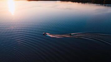 Motor boat on water at sunset. Panoramic view of the evening river with two boats. Motor boat pulling small boat with people. View from above. video