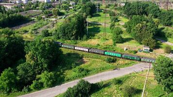 Freight train passing on railway. Cargo train with freight wagons moving among green nature in summer. Aerial view. video