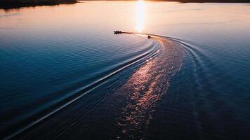 Motion of boats at sunset. Amazing view on the evening river with motor boat leaving paths on water surface. Aerial view. video