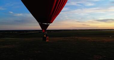 Romantic aerostat at sunset. Hot air balloon in the heart shape with basket travels on beautiful evening nature background in summer. video