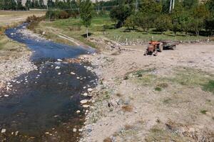 Farming near a stream in Iran with a tractor working the land photo