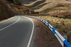 Curved highway winding through the mountainous terrain of Armenia under soft afternoon light photo