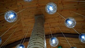 Modern ceiling with light lamp balls. Many round light balls hanging around brick column in the hall. Beautiful glass bulbs on brown background. video