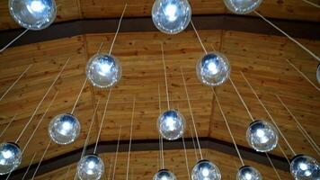Cozy ceiling with many crystal small balls. Round light bulbs hanging on white wires. Modern design of shiny light lamps. video