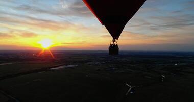 People travel in hot air balloon. Beautiful red aerostat in the form of a heart flying in the sky against orange sunset. video