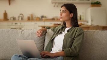 Pensive thinking Indian woman Arabian female ethnic girl user freelancer student businesswoman online business using computer typing laptop at home shopping internet booking food delivery order app video