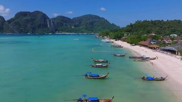 Aerial view of Phi Phi Islands in Thailand, showing turquoise waters, lush green cliffs, small boats, and a clear sky under bright sunlight. video