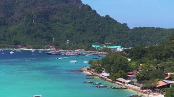 Aerial view of Phi Phi Island, Thailand, showing turquoise waters, lush cliffs, boats in the bay, and a shoreline with small buildings. video
