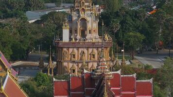 Aerial view of Wat Chalong in Phuket, Thailand, showcasing its ornate spires, golden details, central pagoda, and lush green surroundings. video