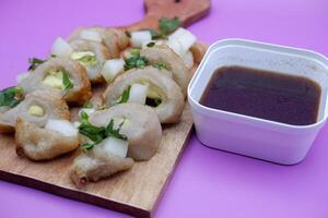 Empek-empek isolated on purple background. typical food from Sumatra, Indonesia. typical food made from fish and flour. food enjoyed with special brown sauce. photo