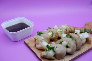 pempek isolated on purple background. a typical food made from fish and flour. a food enjoyed with a special brown sauce. photo