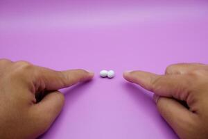 two index fingers are pointing at house lizard eggs on a purple background photo