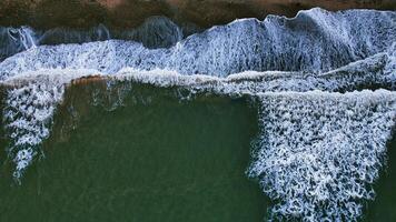 Aerial View of Ocean Waves Breaking on a Dark Sandy Beach photo