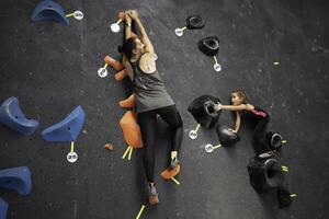 Determined mother and daughter climbing artificial rock wall at gym photo