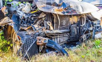 Old damaged rusty car wreck in the grass photo