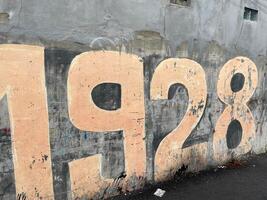 Vintage 1928 Wall Mural A Glimpse into the Past, Weathered Numbers on a Gray Wall, Urban Decay and History photo