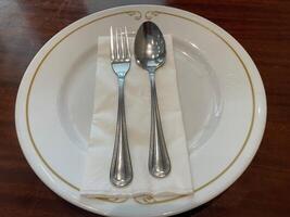 Elegant Table Setting, White Plate with Gold Rim, Silverware, and Napkin photo