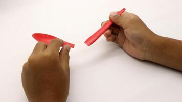 a child's hands are holding two red plastic spoons-1 photo