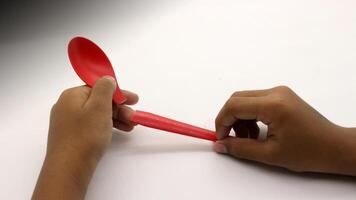 a child's hands are holding two red plastic spoons-3 photo