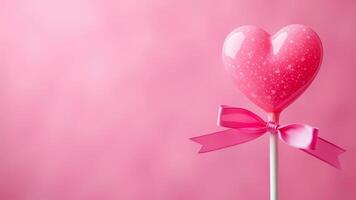 Pink heart lollipop with bow on a pink background. For romantic Valentine's day celebration. Horizontal banner. Copy space photo