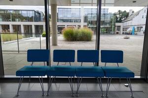 A row of four blue chairs are sitting in front of a window photo
