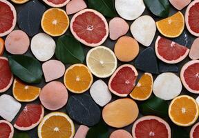 Flatlay of citrus fruits and stones on dark background photo