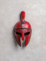 Red ancient greek helmet on a light gray background photo