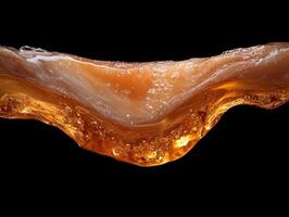 Close up of golden liquid flowing, splashing, and creating waves against a black background photo