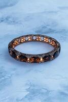 Luxury rose gold bracelet with brown gemstones and diamonds on a light blue background photo