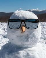 Cool snowman wearing sunglasses in a snowy mountain landscape photo