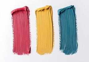 Close up of three vibrant paint strokes in red, yellow, and teal on a white background photo