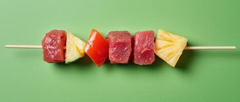 Delicious grilled meat and fruit skewers on green background photo