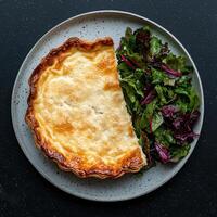 A slice of quiche with a side salad on a gray plate photo
