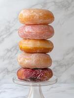 Stack of assorted donuts on a glass cake stand photo