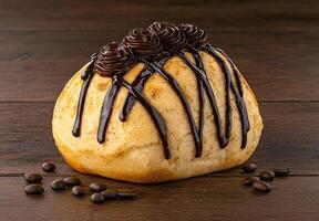 Close up of a delicious chocolate covered pastry with coffee beans scattered on a wooden surface photo