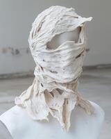 Abstract sculpture of a face covered in textured fabric photo