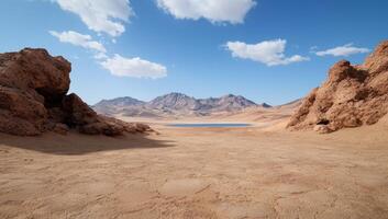 Arid desert landscape with a small lake and rocky outcrops under a bright blue sky photo