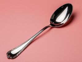 Shiny silver spoon on pink background photo