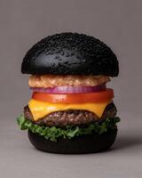 Black burger with cheese, tomato, and onion on a gray background photo