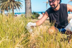 A happy activist is picking up trash in a field taking care of the environment photo