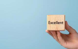 Wooden cube with Excellent rating held against blue background, symbolizing quality and achievement photo