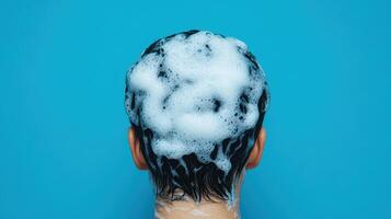Washing hair with foamy shampoo against blue background, creating refreshing vibe photo