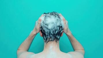 Close up of person washing hair with foamy shampoo, enjoying refreshing experience. vibrant turquoise background enhances soothing atmosphere photo